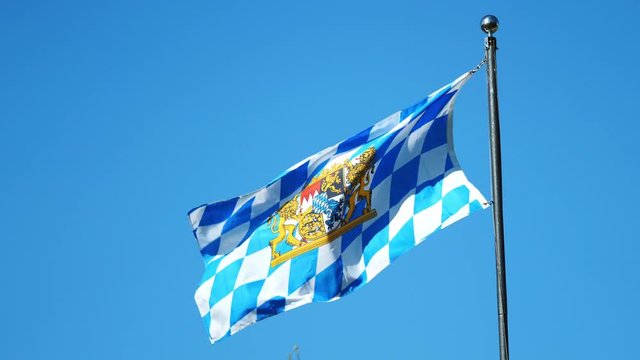 Clip of waggling Bavarian flag on a mast in the wind on sunny cloudless day.