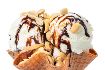 close up of scoops vanilla ice cream decorated chocolate topping and nuts in waffle cone bowl isolated on white background