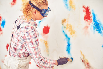 Working woman plastering / painting walls inside the house.