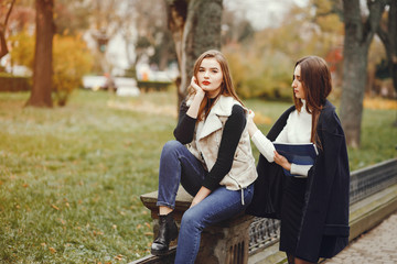 Beautiful girls in a park. Ladies near the fence. Women sitting