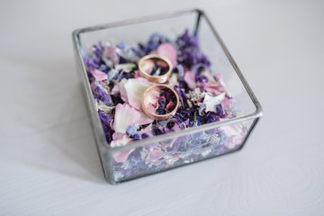 wedding rings are in a wooden box with flower petals