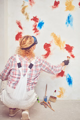 Obraz premium Working woman plastering / painting walls inside the house.