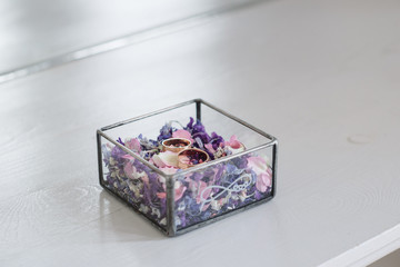 wedding rings are in a wooden box with flower petals