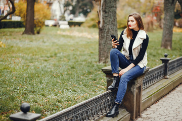 Beautiful girl in a city. Woman with phone. Girl at the fence