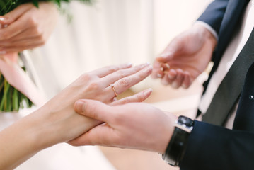 The bridegroom puts the wedding ring on the bride close up. The bride puts the bridegroom on the wedding ring.