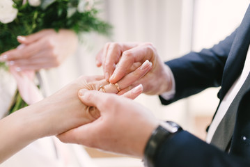 The bridegroom puts the wedding ring on the bride close up. The bride puts the bridegroom on the wedding ring.