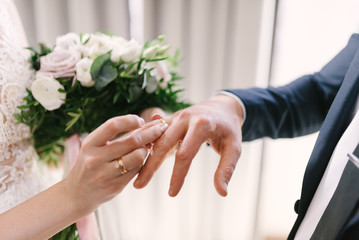 The bridegroom puts the wedding ring on the bride close up. The bride puts the bridegroom on the wedding ring.