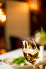 a glass of white wine on the background of dinner in a restaurant