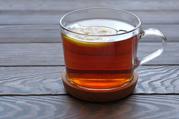 glass mug with tea, tea with  a lemon on a wooden surface