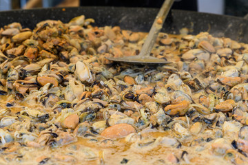 Large group of cooked mussels with tomato sauce at a street food festival, ready to eat seafood