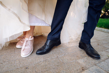 The legs of the bride in a wedding dress in shoes