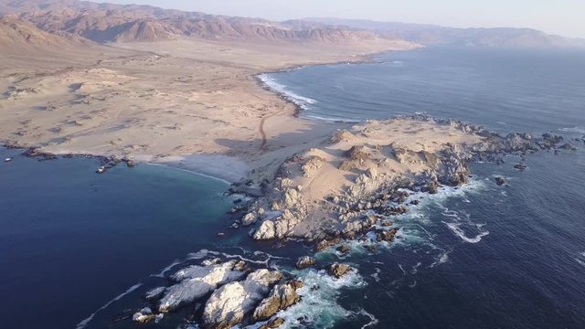 Las Tortolas beach aerial footage at Atacama Desert the sunset ray lights illuminate this amazing and idyllic beach in the middle of the desert, an arid awe landscape crashed by Pacific Ocean waters