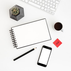 Minimal workspace; white desk, table with spiral notebook, coffee, cactus and smartphone screen for mock up or product monage. Flat lay.