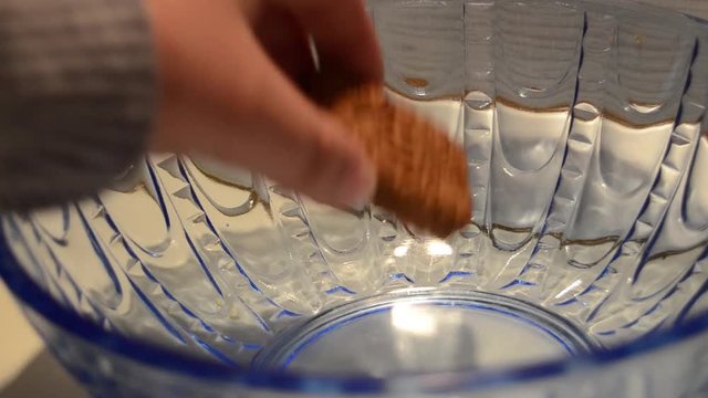 Woman hand taking last cookie buiscut from blue glass bowl shugar addiction concept