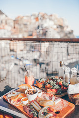 Tasty italian snack. Fresh bruschettes, cheeses and meat on the board in outdoor cafe with amazing view in Manarola