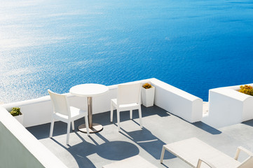 Two chairs with table on the terrace overlooking the sea. Santorini island, Greece.