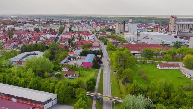 Flying backward with drone and filming hyperlapse in the small city Brcko district in Bosnia and Hezegovinia, above cars and trucks and railroad. There is oil fabric in frame,and river Sava.