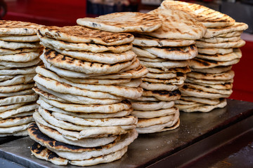Home made pita bread displayed with different types of meat, for sale at a street food market
