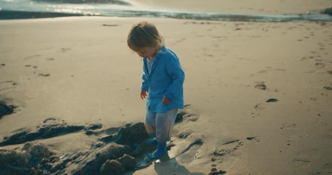 Little toddler in socks getting feet wet on beach