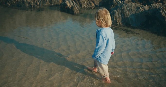 Little toddler and his mother walking on the beach