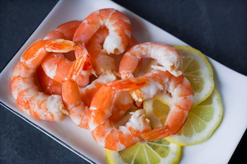 cooked peeled shrimp in a plate with lemon close up