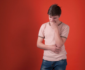 worried teenager in beige t shirt standing and looking away on orange background with copy space
