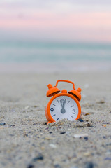 Alarm clock on the sea beach in the summer during sunset