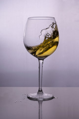 Splash of white wine in a glass on the table
