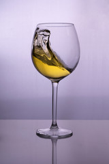 Splash of white wine in a glass on the table