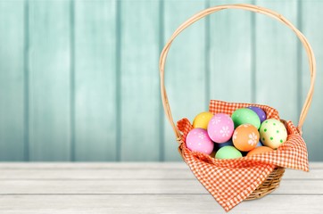 Basket with colorful eggs on white desk