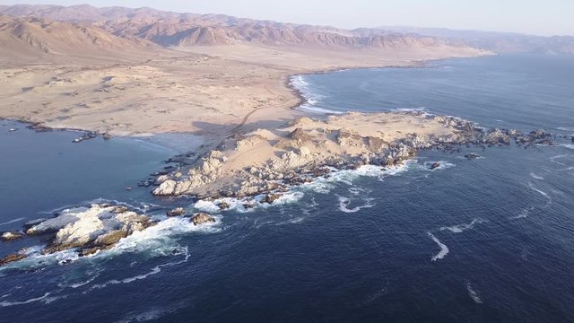 Las Tortolas beach aerial footage at Atacama Desert the sunset ray lights illuminate this amazing and idyllic beach in the middle of the desert, an arid awe landscape crashed by Pacific Ocean waters