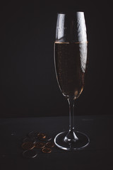 Glass of champagne against a dark background with coins. concept of financial victory or success