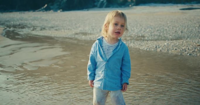 Little toddler standing on the beach pulling funny face