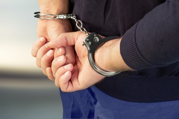 Cropped image of male hands in handcuffs behind his back