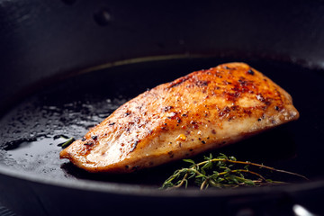 Roasted Turkey breast with a Golden crust and seasonings on a black pan.