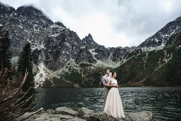 Young wedding couple posing on the shore of the lake Morskie Oko. Poland, Tatra