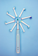 An electric toothbrush and multi-colored replaceable nozzles on blue background