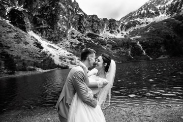 The groom kissing his young bride, on the shore of the lake Morskie Oko. Poland. Black and white photo