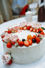 wedding cake with berries and flowers on white background