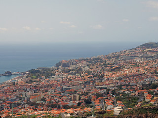 Fototapeta premium a view of funchal from above showing the city and hills with ocean and blue sky in the distance