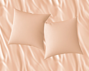 Two blank beige soft square satin pillows on bedsheet, messy bed sheets,  mockup for your design, 3D render