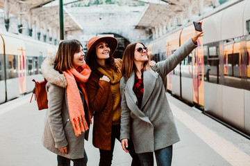 A group of young friends taking a selfie while waiting for their train to leave at the Oporto station in Portugal. Travel photography. Lifestyle