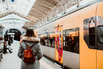 .Young woman with short hair and grey coat waiting around the platform while is about to take a...
