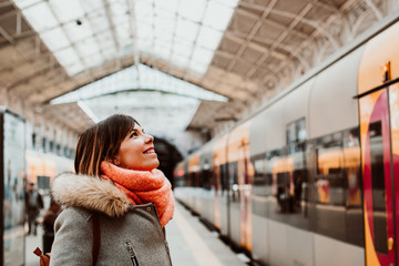 .Young woman with short hair and grey coat waiting around the platform while is about to take a train at the train station of oporto, portugal. Lifestyle