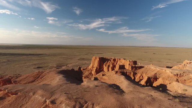 Man standing on the edge of flaming cliffs Bayanzag aerial drone shot sunset Mongolia