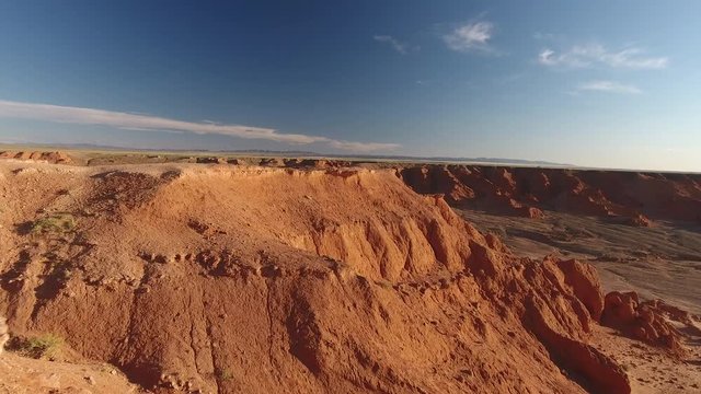Low aerial drone shot over the flaming cliffs Bayanzag Mongolia sunset time archeological site