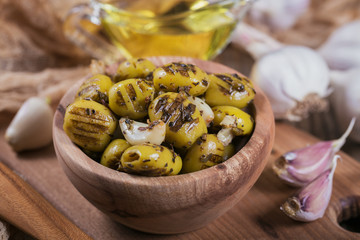 Grilled olives with garlic, olive oil and spices on wooden background