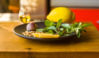 Fresh ingredients for preparing Italian pesto sauce - lemon basil sprigs, peeled seeds of cedar nuts, large garlic clove, Greek olive oil, Parmesan cheese