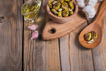 Grilled olives with garlic, olive oil and spices on rustic wooden table