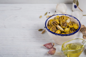 Grilled olives with garlic, olive oil and spices on rustic wooden background